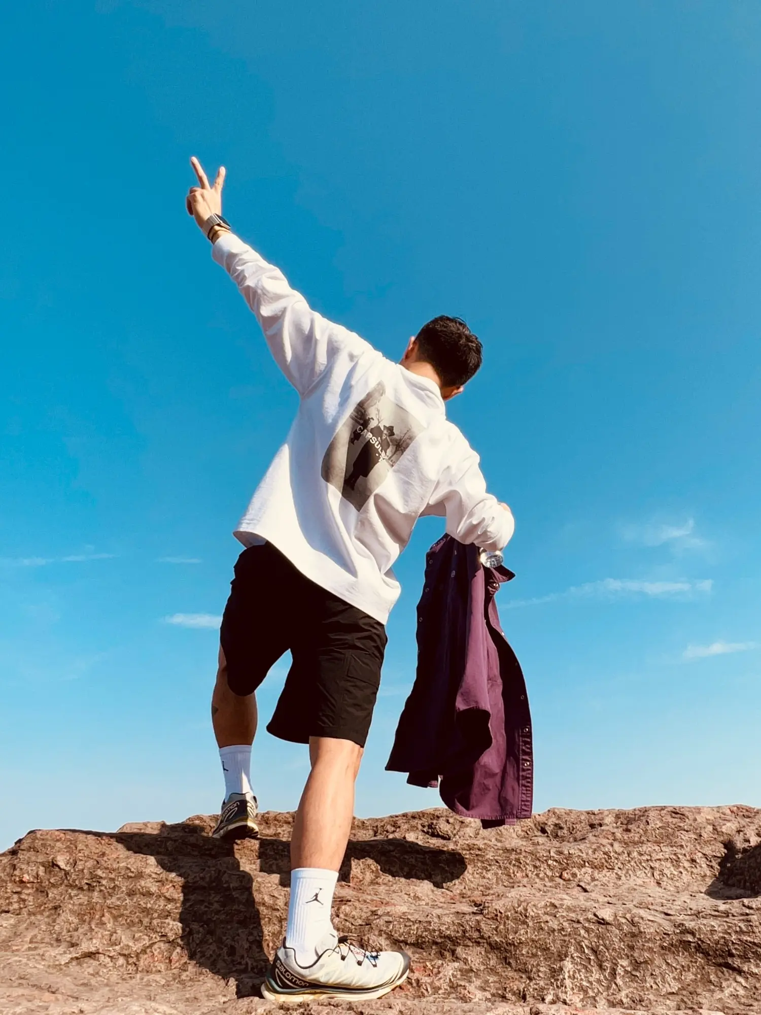 Bobby climbing onto a rock beneath a blue sky