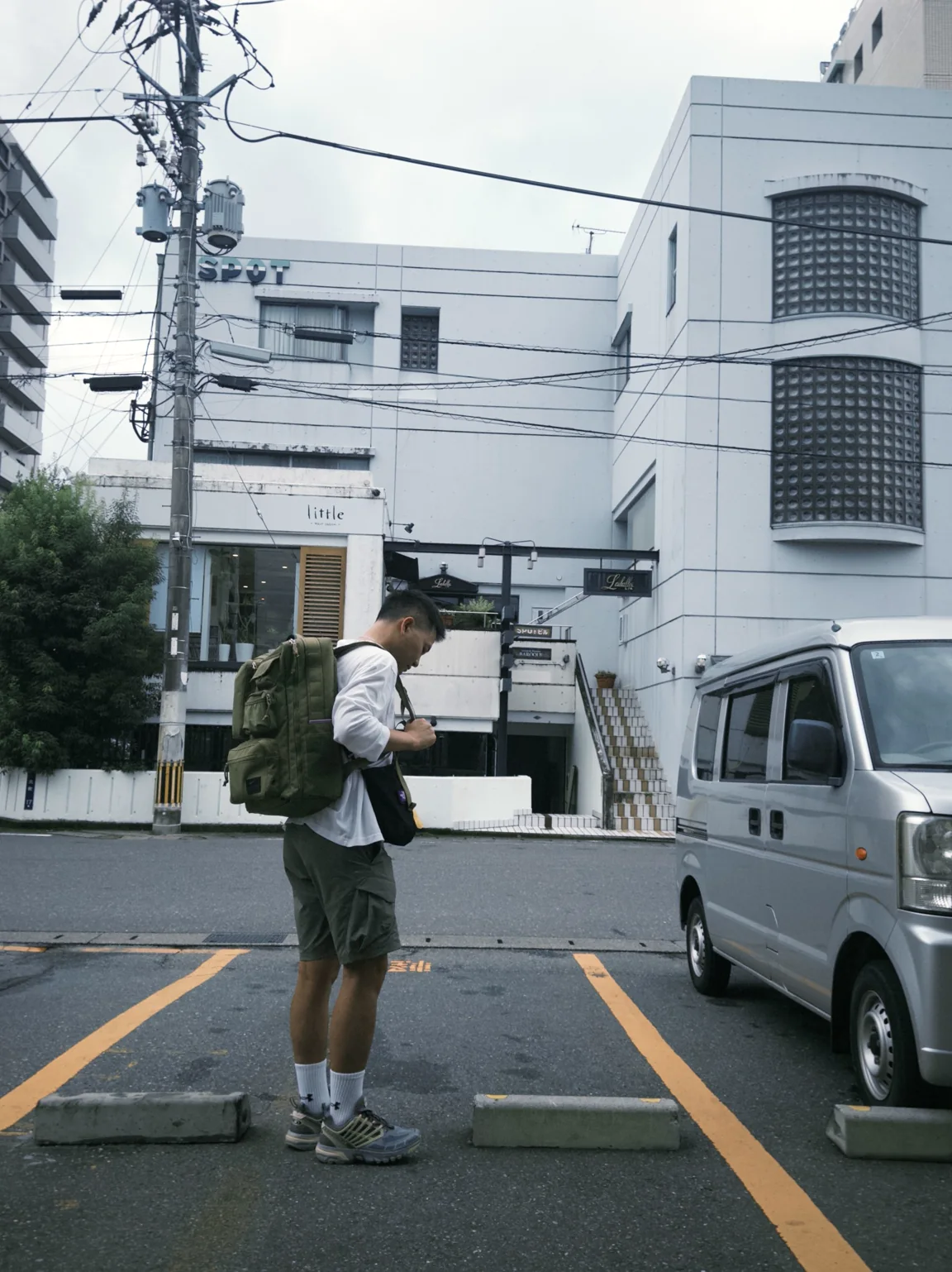 Bobby walking through a quiet Japanese street with a green backpack